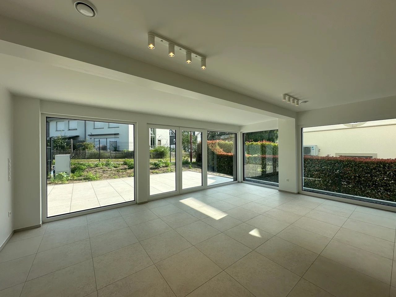 Salon spacieux avec carrelage clair et larges baies vitrées donnant sur le jardin