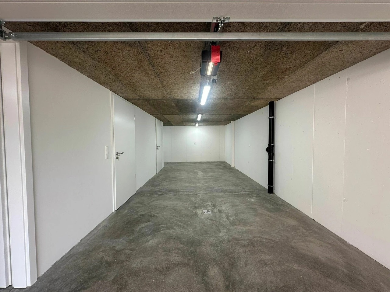 Garage vide avec sol en béton et murs blancs