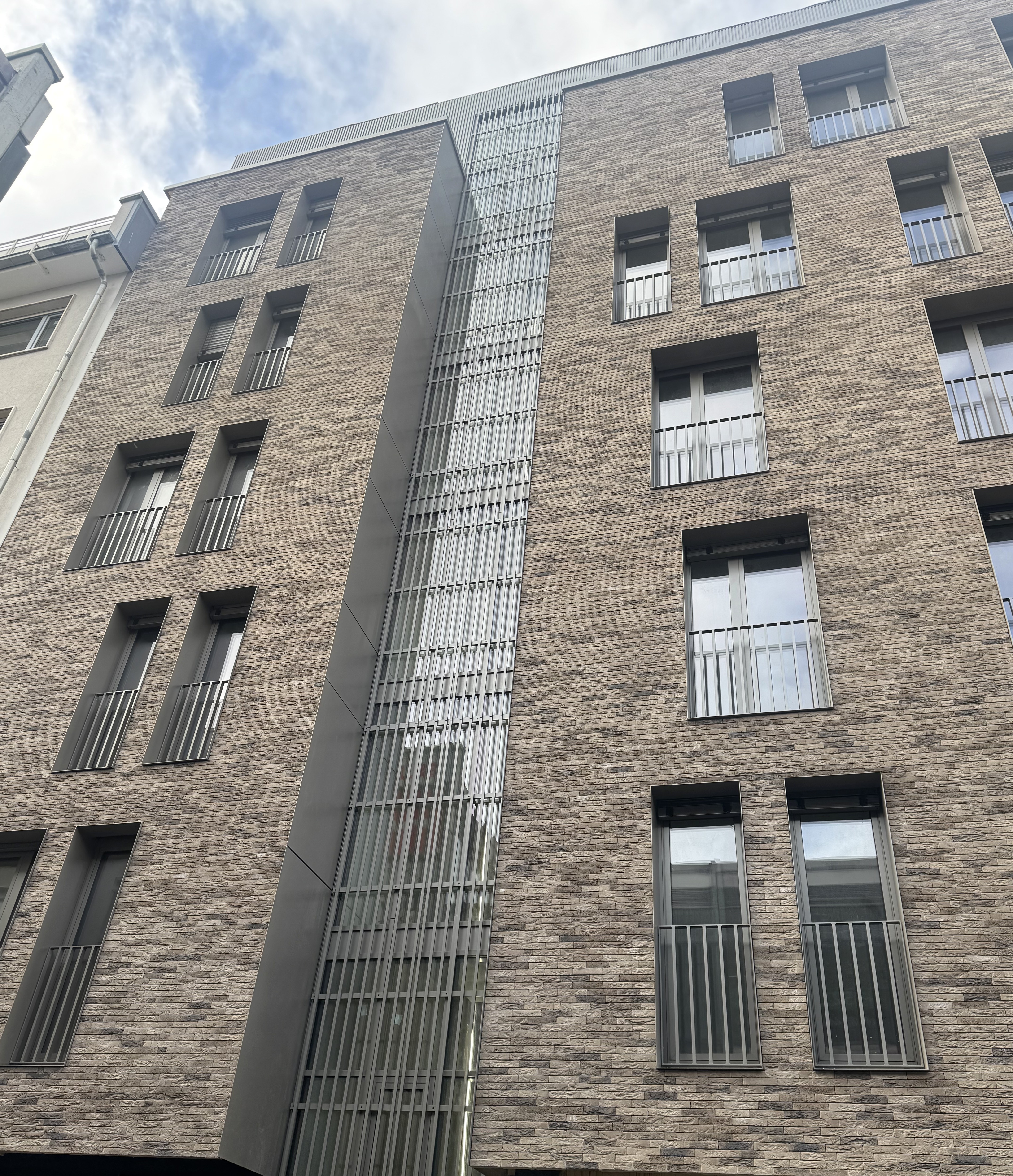 Façade extérieure moderne de la Résidence Place Saint-Pierre-et-Paul avec briques beiges et éléments métalliques verticaux